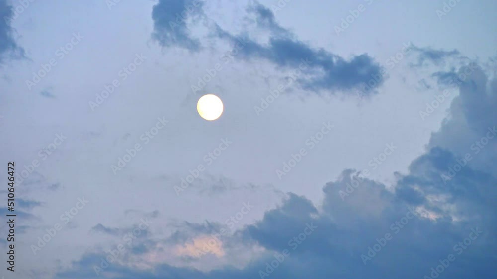 Clouds float across the evening sky with a full moon Clouds float across the evening sky with a full moon