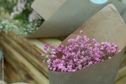 Bukiet suszonych różowych kwiatów w szarym papierze.