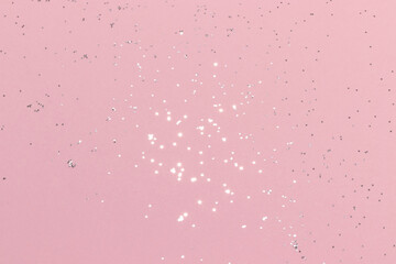 Sparkling silver glitter on pink background. Holiday blurred lights
