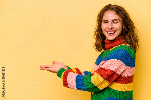 Young caucasian woman isolated on yellow background holding a copy space on a palm.