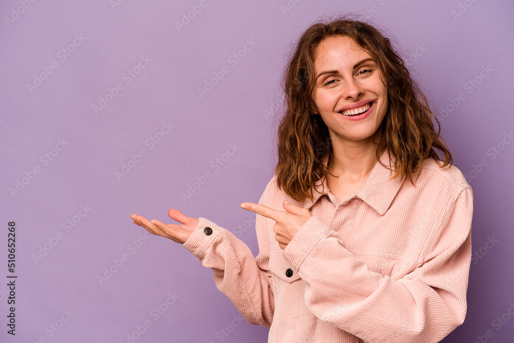 Young caucasian woman isolated on purple background excited holding a copy space on palm. Young caucasian woman isolated on purple background excited holding a copy space on palm.