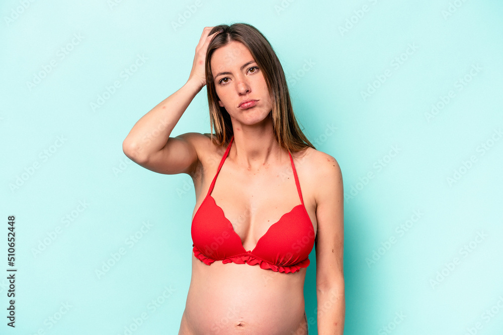 Fototapeta premium Young caucasian pregnant woman wearing bikini isolated on blue background being shocked, she has remembered important meeting.