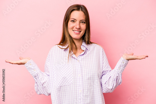 Young caucasian pregnant woman isolated on white background makes scale with arms, feels happy and confident.