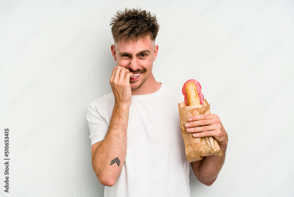 Young caucasian man holding a sandwich isolated on white background biting fingernails, nervous and very anxious. Young caucasian man holding a sandwich isolated on white background biting fingernails, nervous and very anxious.