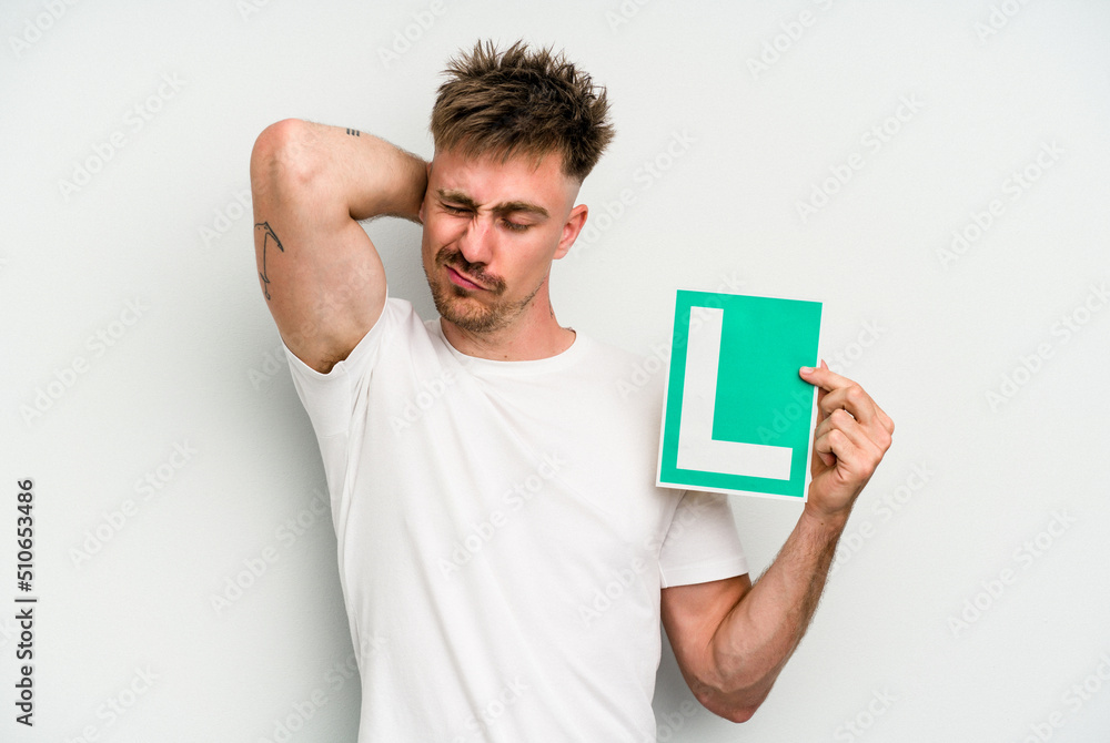 Young caucasian man holding L placard isolated on white background touching back of head, thinking and making a choice. Young caucasian man holding L placard isolated on white background touching back of head, thinking and making a choice.