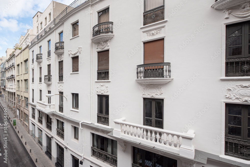 Naklejka premium White painted vintage building facade in a narrow street in the center of Madrid
