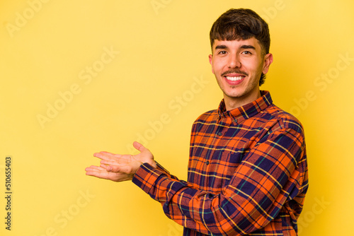 Young caucasian man isolated on yellow background holding a copy space on a palm.
