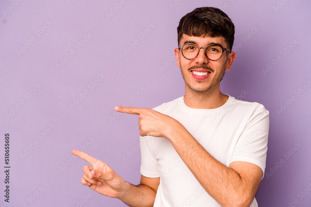 Young caucasian man isolated on purple background excited pointing with forefingers away. Young caucasian man isolated on purple background excited pointing with forefingers away.