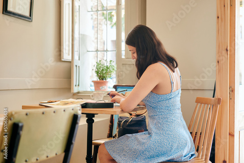 Woman draws while eating breakfast in a coffee shop photo