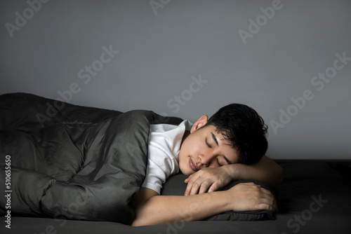 Side view of Asian man sleeping in his bed with a bright expression on his face at night. concept of health care with at least eight hours of bed rest.
