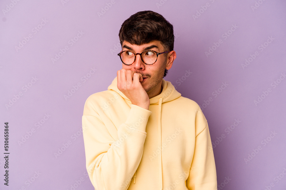 Fototapeta premium Young caucasian man isolated on purple background biting fingernails, nervous and very anxious.