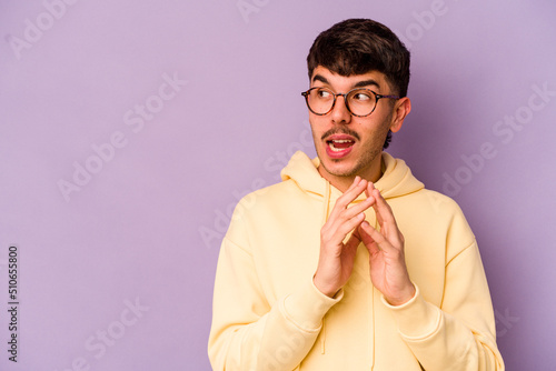 Young caucasian man isolated on purple background making up plan in mind, setting up an idea.