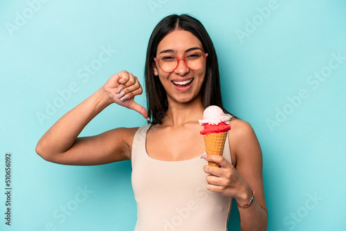 Young hispanic woman holding an ice cream isolated on blue background feels proud and self confident, example to follow.