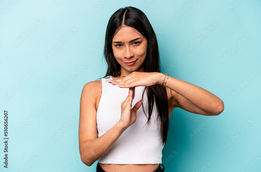Young hispanic woman isolated on blue background showing a timeout gesture. Young hispanic woman isolated on blue background showing a timeout gesture.