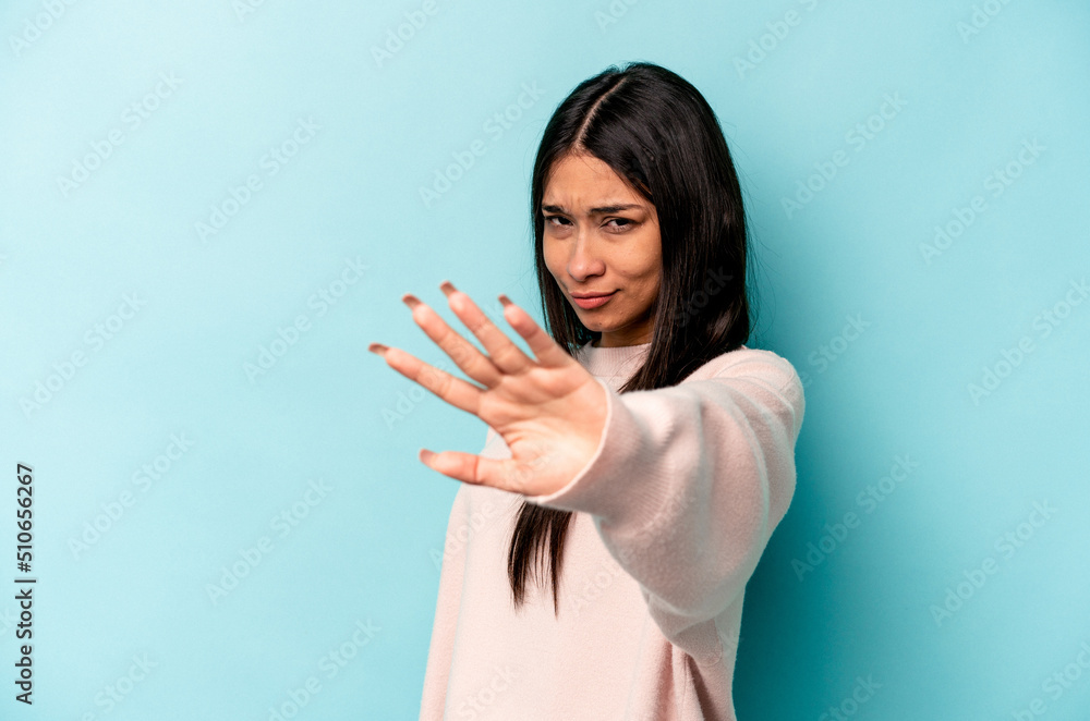 Young hispanic woman isolated on blue background rejecting someone showing a gesture of disgust. Young hispanic woman isolated on blue background rejecting someone showing a gesture of disgust.