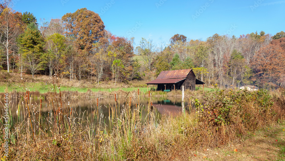 Farm scene in fall with pond and old cabin under blue sky. Farm scene in fall with pond and old cabin under blue sky.