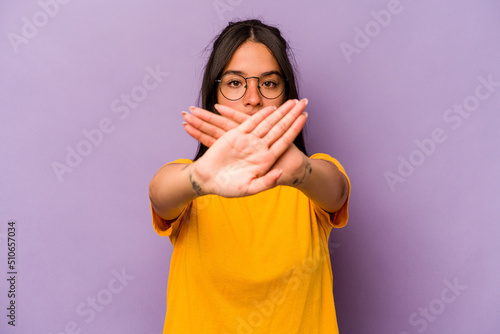 Young hispanic woman isolated on purple background doing a denial gesture