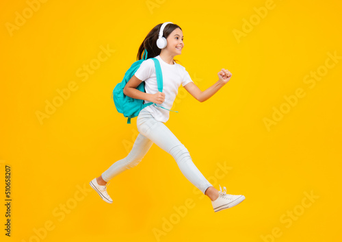 School leisure. Happy teenager portrait. School girl in headphones on isolated studio background. School and music concept. Jump and run, jumping child.