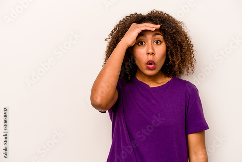 Young African American woman isolated on white background looking far away keeping hand on forehead. © Asier