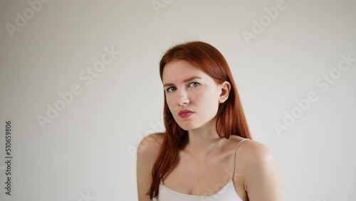 An adult girl is displeased and incredulous looks into the camera and listens to the interlocutor via video link. Beautiful young woman carefully looks into the camera.  photo