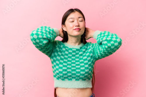 Young Chinese woman isolated on pink background feeling confident, with hands behind the head. © Asier