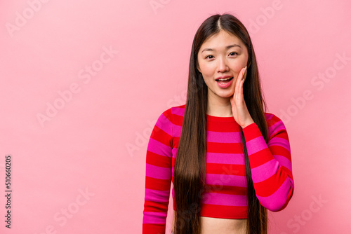 Young Chinese woman isolated on pink background shouts loud, keeps eyes opened and hands tense. © Asier