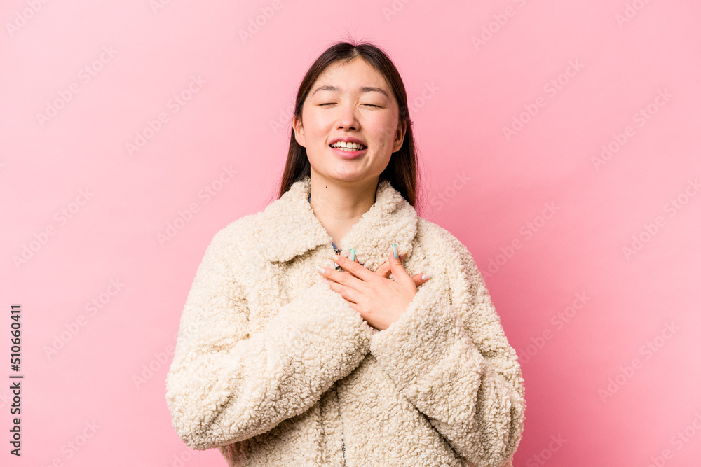 Young Chinese woman isolated on pink background laughing keeping hands on heart, concept of happiness. Young Chinese woman isolated on pink background laughing keeping hands on heart, concept of happiness.