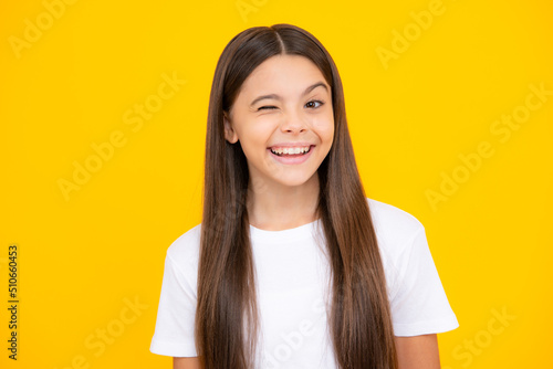 Funny face. Teenager child girl close one eye, winks and smiling. Human facial emotions concept. Funny winking face gesture.