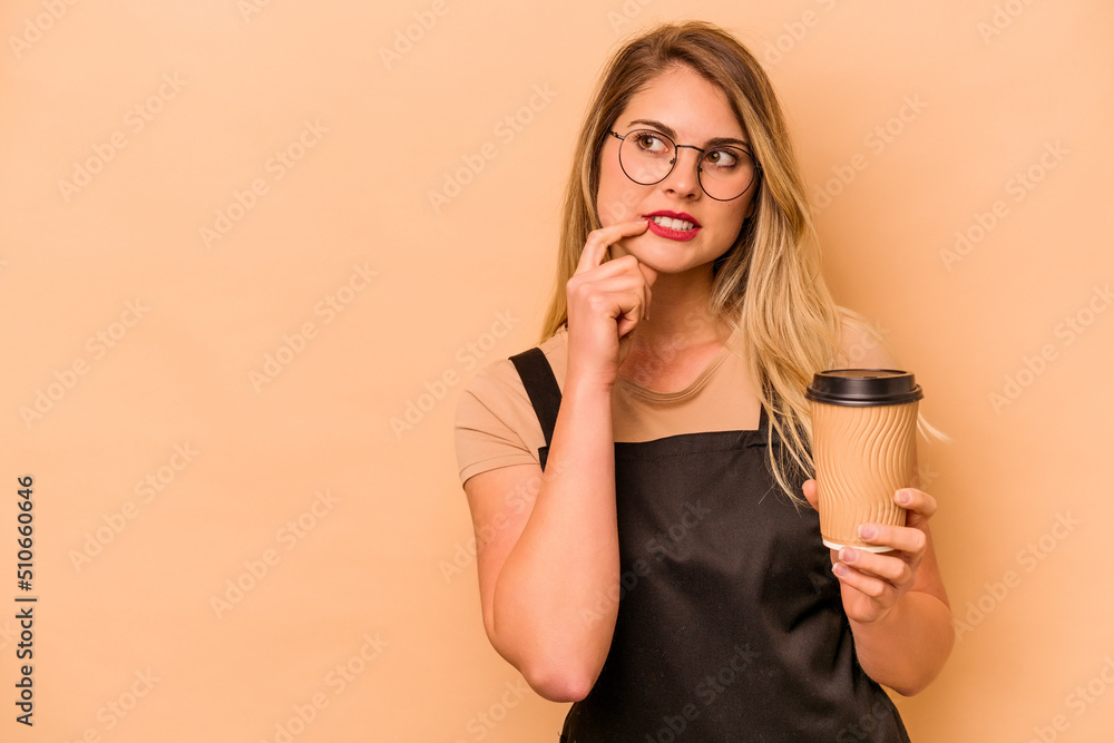 Restaurant waiter caucasian woman holding a take away coffee isolated on beige background relaxed thinking about something looking at a copy space. Restaurant waiter caucasian woman holding a take away coffee isolated on beige background relaxed thinking about something looking at a copy space.