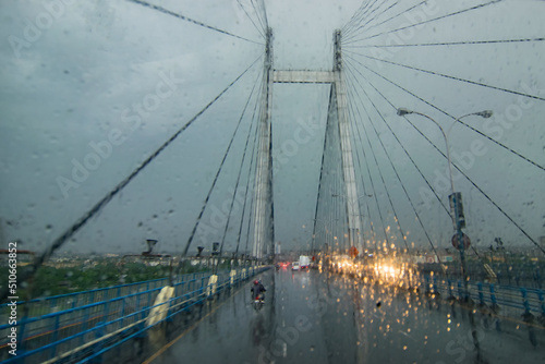 Vidyasagar Setu (Bridge) over river Ganges, known as 2nd Hooghly Bridge in Kolkata,West Bengal, India. Abstract image shot aginst glass with raindrops all over it, monsoon image of Kolkata. photo