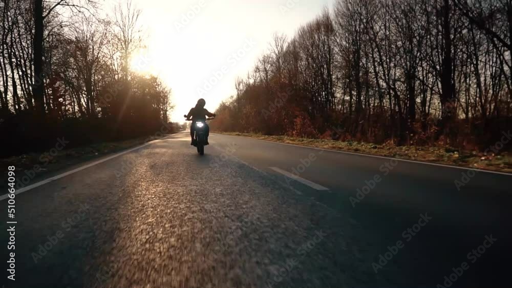 Motorcyclist riding fast at sunset on country road, motorcycle adventure lifestyle Motorcyclist riding fast at sunset on country road, motorcycle adventure lifestyle