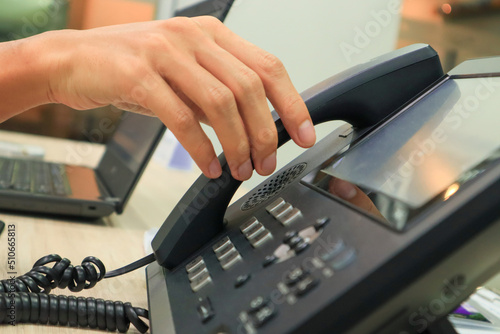Close-up IP phone on the work desk, The human hand lifted the telephone placed on the table, Hang up the telephone cord placed on the work desk.
