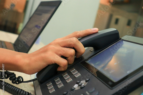 Close-up IP phone on the work desk, The human hand lifted the telephone placed on the table, Hang up the telephone cord placed on the work desk.