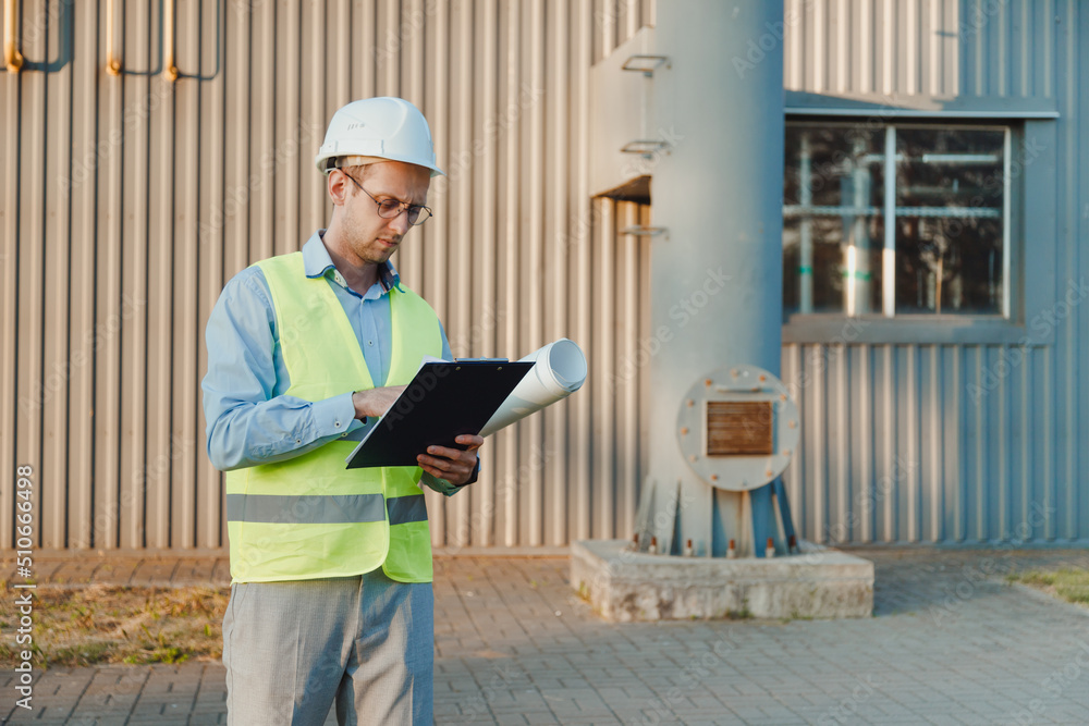 Foreman supervisor in suit and helmet on head, holding folder with documents at industrial factory. Foreman supervisor in suit and helmet on head, holding folder with documents at industrial factory.