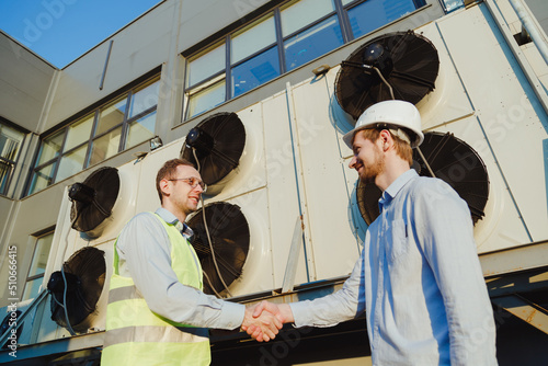 Obraz na płótnie The customer greets civil engineer with a handshake at industrial refrigeration machine near the building w salonie