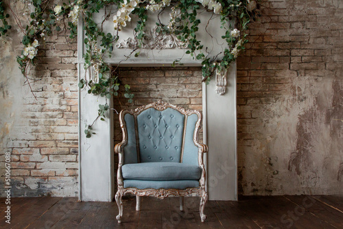 Old antique armchair furniture against a light gray grunge wall, stucco, and vines with flowers Abstract empty room