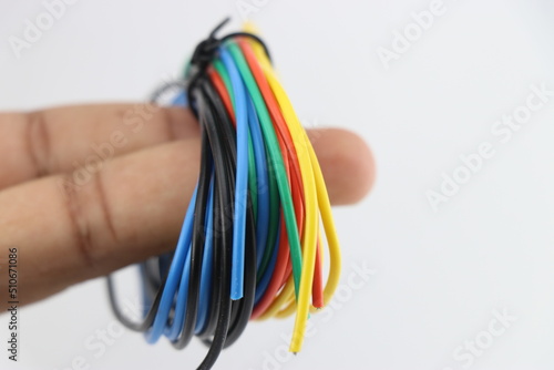 Different colored wires for electronic component connections are held in hand on white background