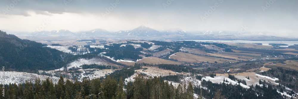 Aerial view on snowy valley with mountain range shrouded in clouds in background, Slovakia, Europe