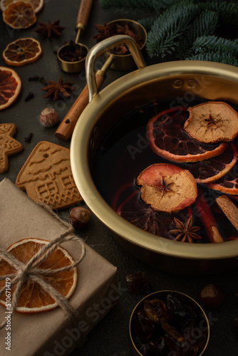 Christmas hot alcoholic drink mulled wine in a pan with citruses, aromatic spices, cinnamon and dried fruits among the spruce branches