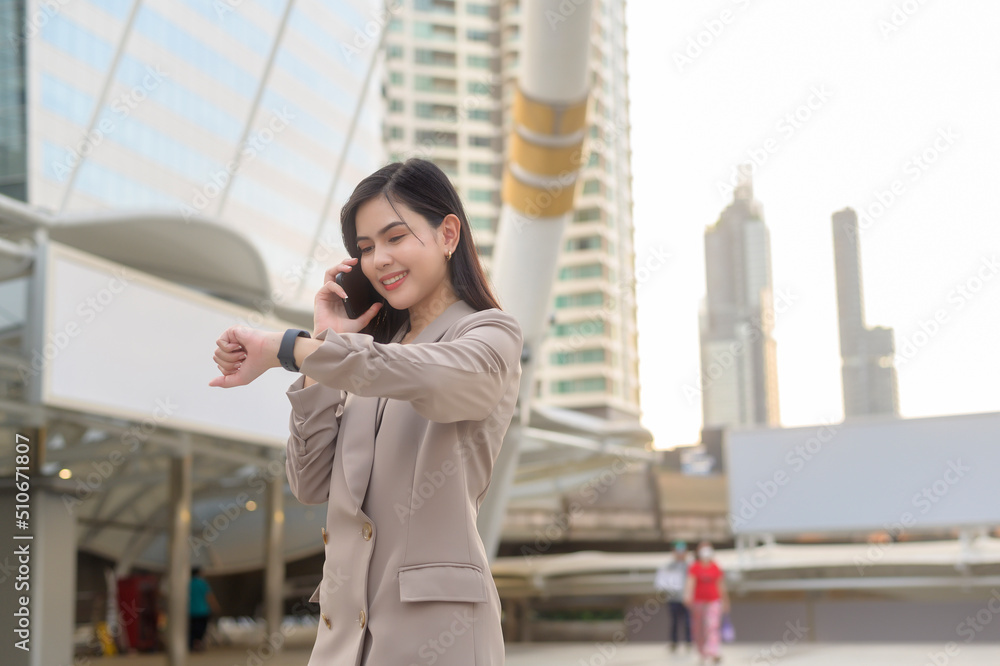 Fototapeta premium A young beautiful businesswoman is using Smart phone in Modern city , business technology , city lifestyle concept