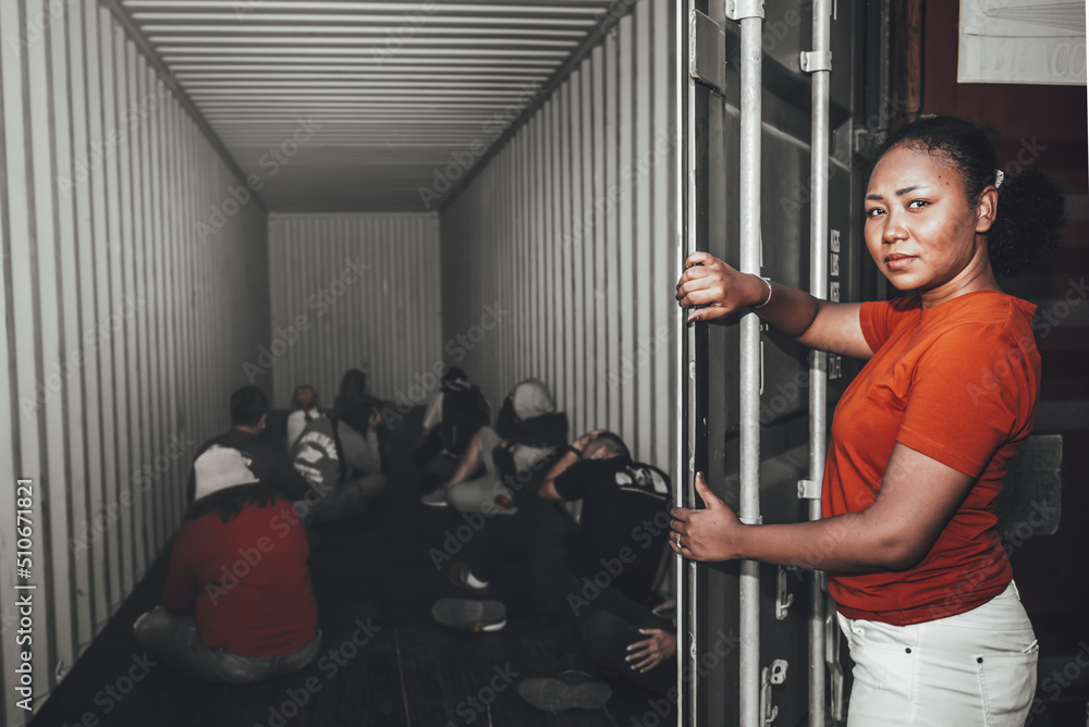 An African women Opening the door of a container, inside of which several people were sitting, to human trafficking and illegal immigration concept. - obrazy, fototapety, plakaty 