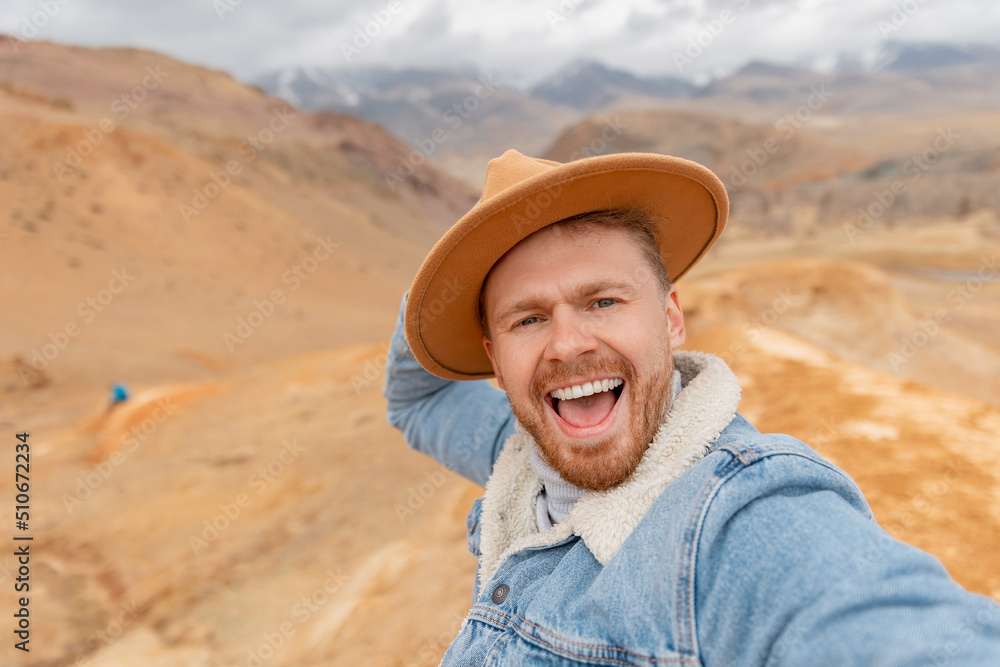 Concept Travel selfie photo, Happy Traveler hipster man in hat background mountains