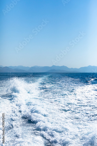 Fototapeta Naklejka Na Ścianę i Meble -  View from a high-speed ship on the blue sea with a mountainous coast in the background
