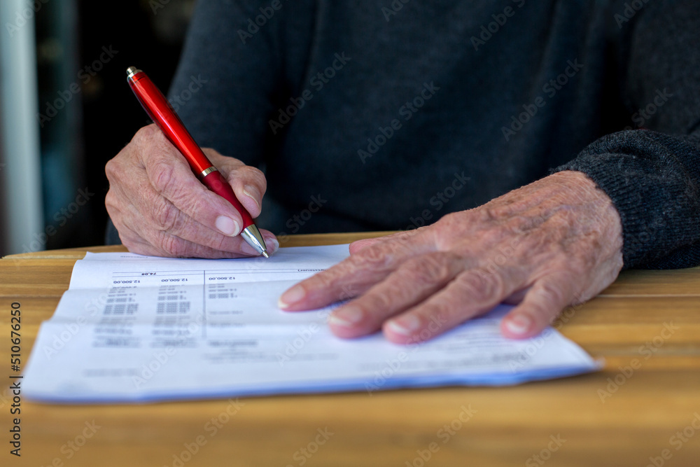 close-up of older womans hand signing a paper close-up of older womans hand signing a paper