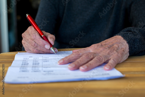 close-up of older womans hand signing a paper