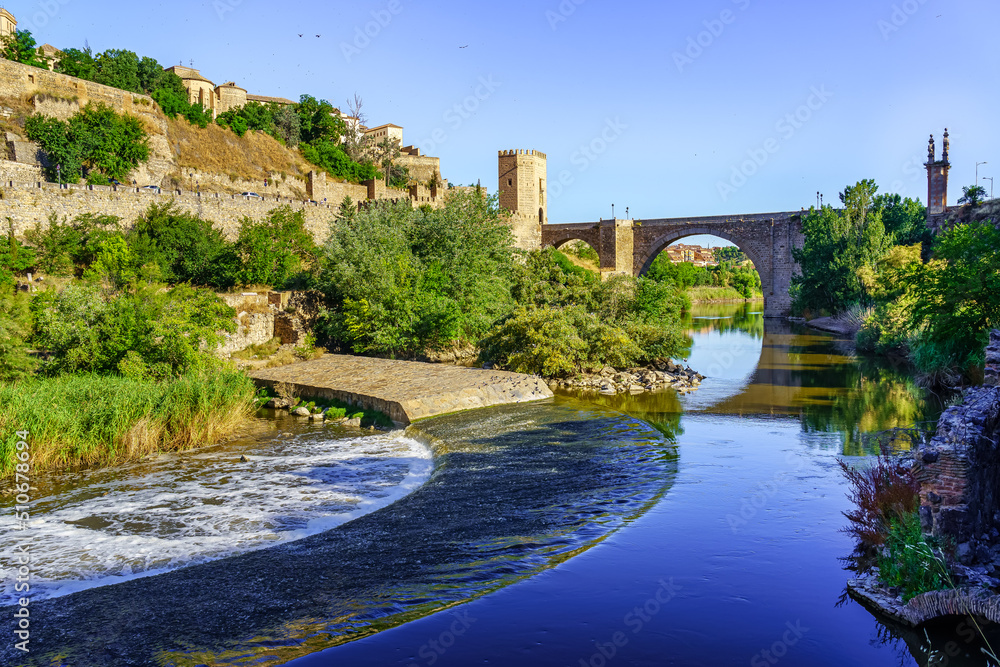 Fototapeta premium Tagus River as it passes through the medieval city of Toledo on a blue sky day.
