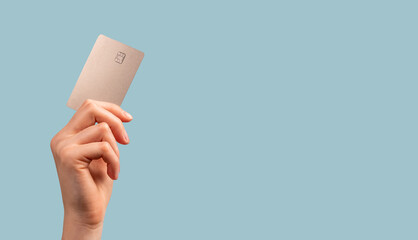 Banner with hand holding credit card mockup with chip on blue background. Buying at stores, making transactions at terminals. Secure payments. High quality photo