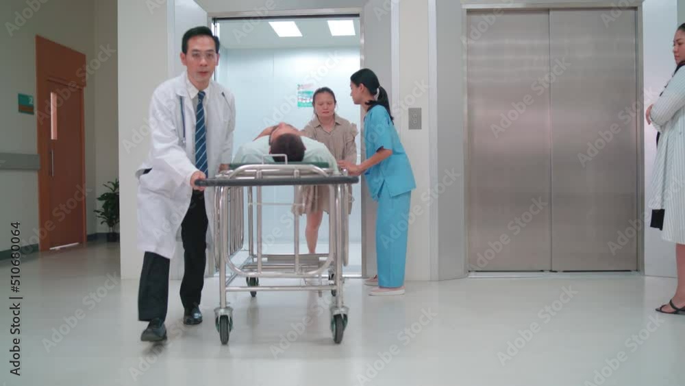 Hospital emergency team include doctor and nurse move or transport patient on mobile bed out from elevator and go along hallway with other people in the area. Hospital emergency team include doctor and nurse move or transport patient on mobile bed out from elevator and go along hallway with other people in the area.