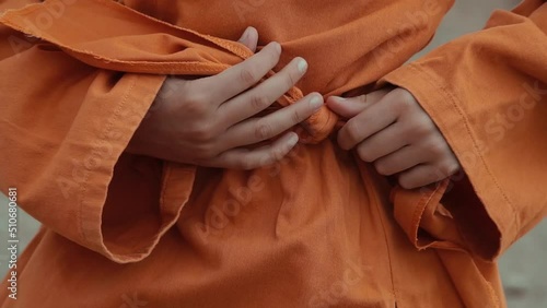 Boy tying orange belt kimono close up
