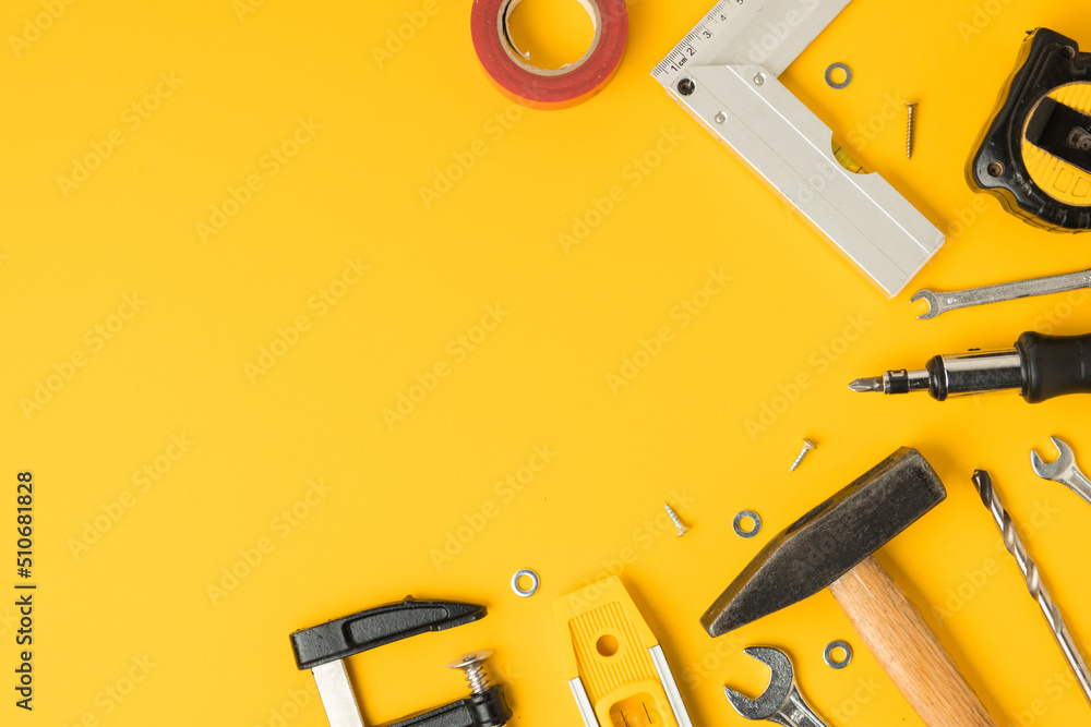 Handyman's tools. Flat lay of clamps, wrench, screwdriver, drill, angle, bubble level and tape measure on yellow background. Happy Father's Day. Free space  for you text